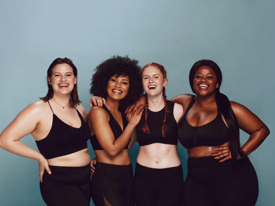 Quatre femmes souriantes célébrant leur corps — body positivity